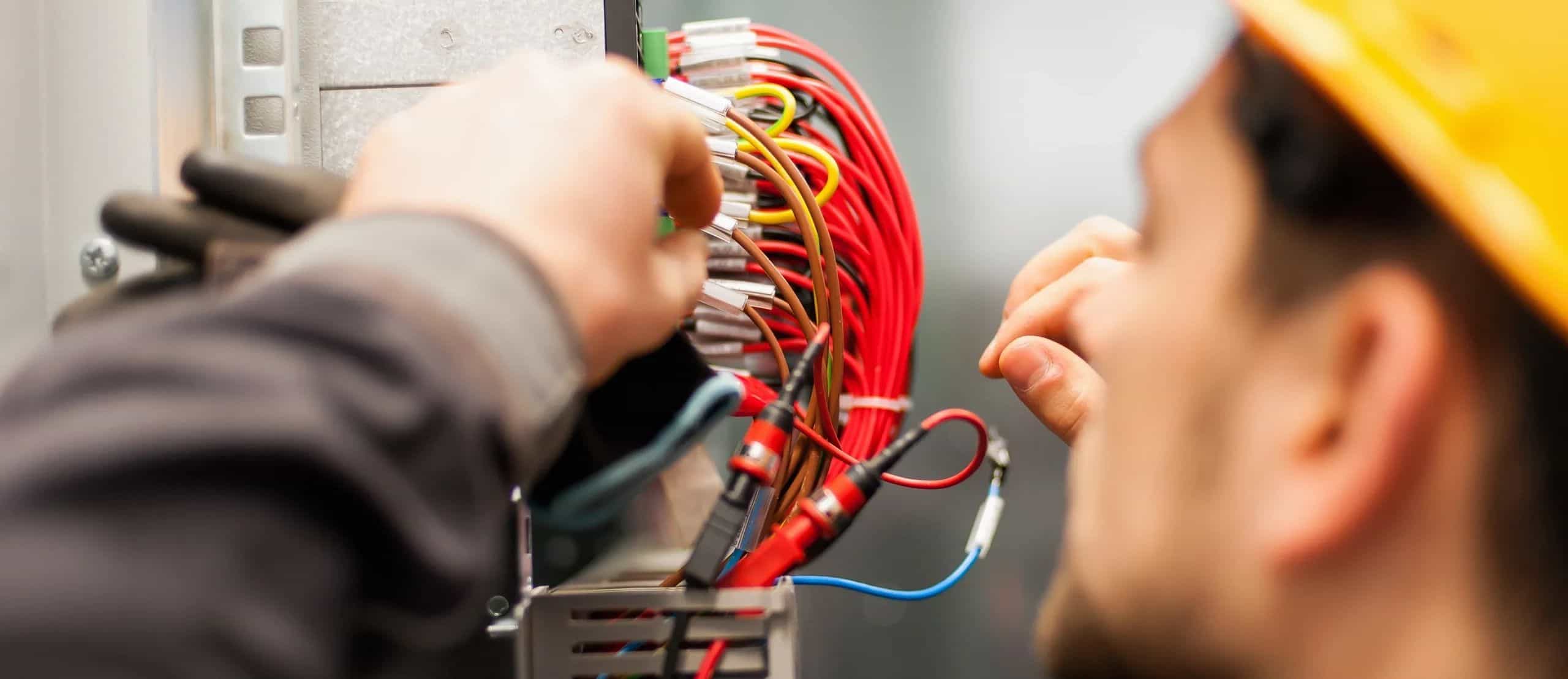 Low voltage technician terminating wiring inside a commercial electrical panel